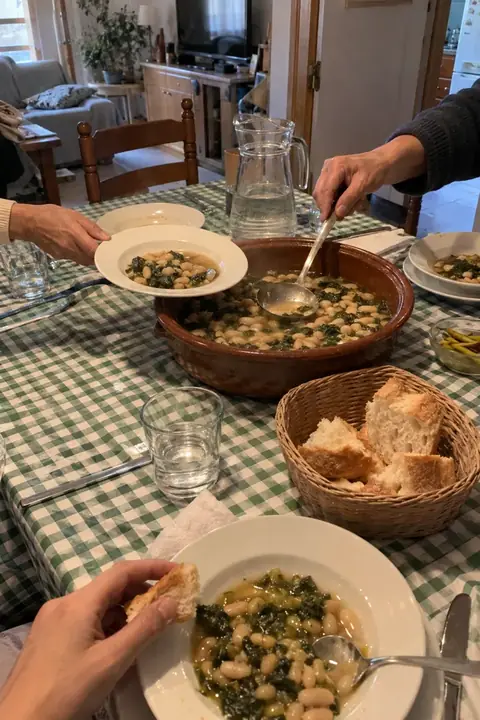 Mesa de domingo con mantel de cuadros verdes y una cazuela de judías con acelgas en el centro